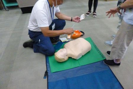 AEDの使い方の様子。講師が使い方を教えている。 AEDの使い方の様子。講師が使い方を教えている。